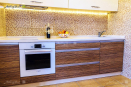 Кухонная мебель со светлыми верхними фасадами и нижними с текстурой дерева из пластика Arpa и крашенного МДФ
